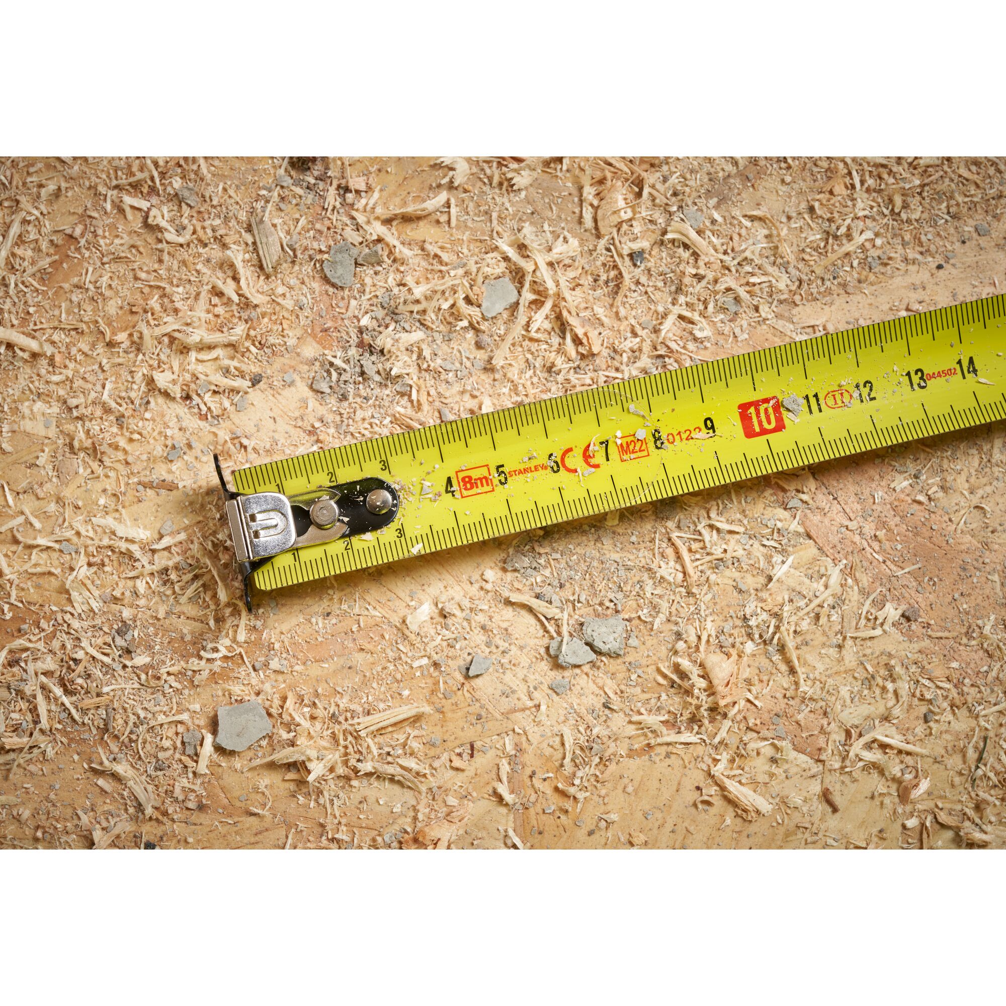 STANLEY STHT37232 tape measure photography showing yellow blade on sawdust surface.